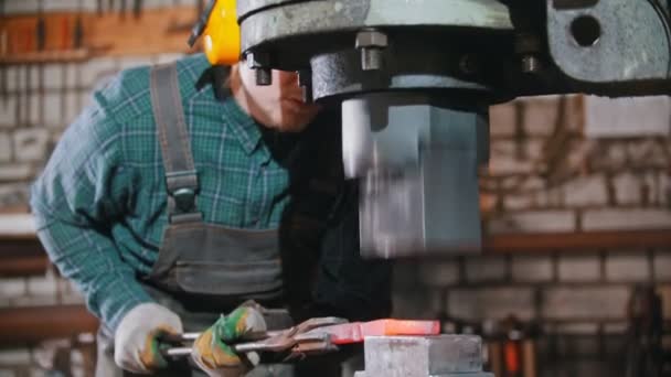 Industria de forja: un herrero hombre que pone la pieza de metal caliente bajo la presión de una gran máquina de forja industrial — Vídeos de Stock