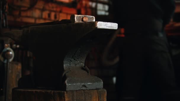 Forging industry - a man blacksmith working indoors - hammer and anvil on the foreground — Stock Video