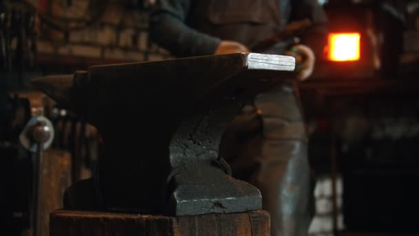 Производство ковки - человек кузнец кладет свои инструменты на наковальню и смотрит в камеру — стоковое видео