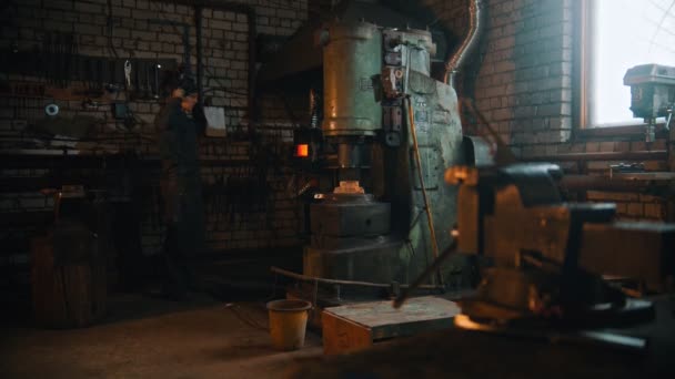 Kování průmyslu - muž kovář nasadit své ochranné sluchátka — Stock video