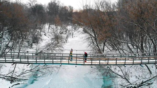 Two young women standing on the snowy bridge in the forest — Stockfoto