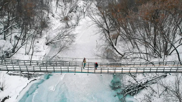 Two young women standing on the snowy bridge in the winter forest — Stockfoto