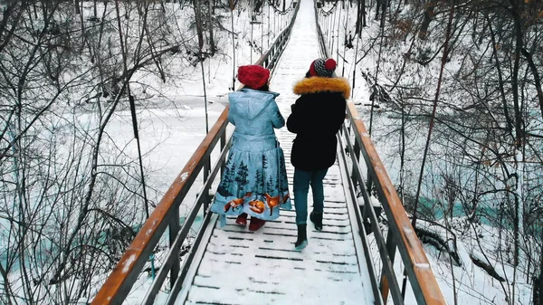 Dos mujeres jóvenes tomando bebidas calientes y caminando por el puente — Foto de Stock