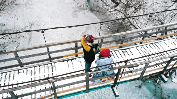 Two women students drinking hot drinks and walk on the snowy bridge — Stockfoto