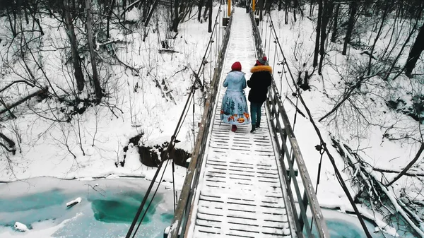 Two young women students walk on the bridge in the winter forest — Stockfoto
