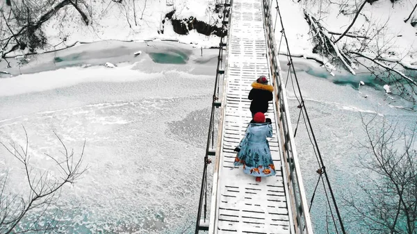 Two young women students walking on the bridge in the winter forest — Stockfoto