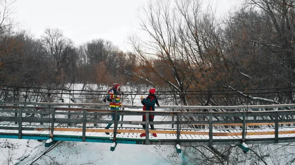 Дві молоді барвисті жінки стоять на сніжному мосту в зимовому лісі — стокове фото