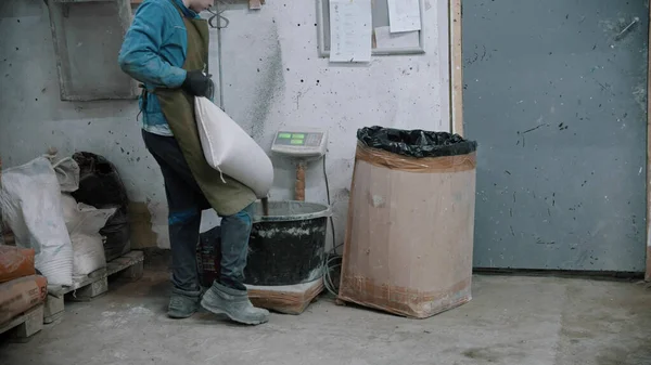 Betonářský průmysl - dělník dává suchý cement do kbelíku — Stock fotografie