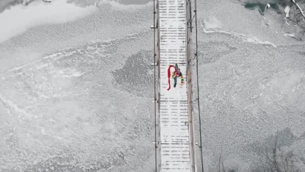 Две красочные женщины бегут по снежному мосту — стоковое видео