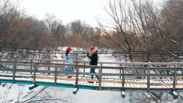 Дві молоді жінки ходять по мосту в лісі і дивляться навколо — стокове відео