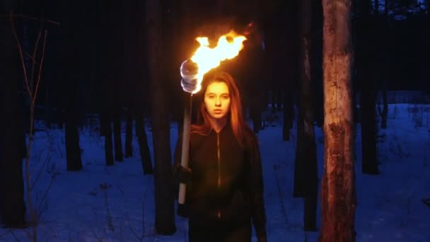 A beautiful woman with torch walking to a camera in winter forest — 图库视频影像
