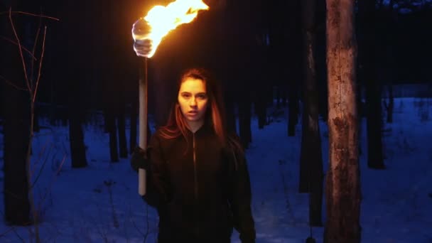 A pretty woman with torch walking to a camera in winter forest — 图库视频影像