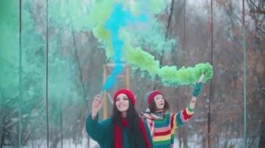 Two young women having fun with smoke bombs outdoors