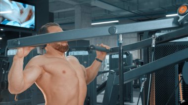 Spor salonunda vücut geliştirme egzersizi yapan sakallı çekici bir adam.