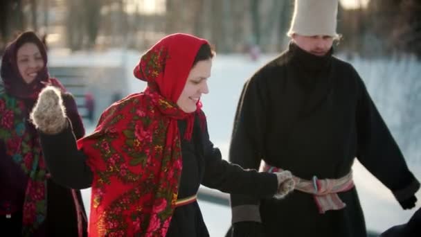 Російський фольклор - люди в яскравому одязі взимку в парку танцюють народні танці — стокове відео