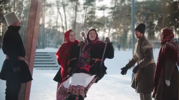 Folklore ruso - Chica rusa balanceándose y todo el mundo se ríe en un día soleado — Vídeo de stock