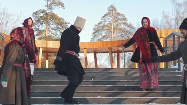 Russian folk - men and women in traditional Russian clothes are dancing on the stairs in winter — Stock Video