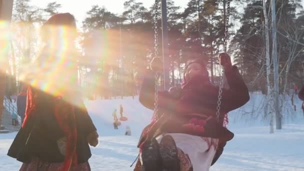 Ryska folket - lycklig kvinna i en ljus halsduk rider på en gunga och skrattar — Stockvideo