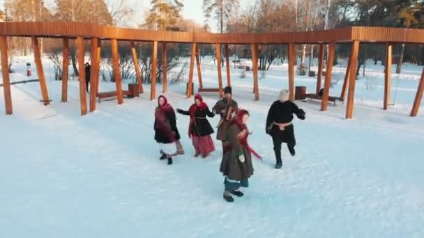 Russische folklore - gelukkige Russen in kostuums dansen in het snowpark — Stockvideo
