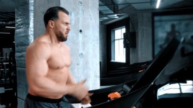 Koşu pistinde koşan sakallı, genç bir vücut geliştirici.