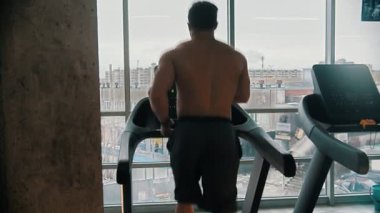 Koşu bandında koşan bir vücut geliştirici.