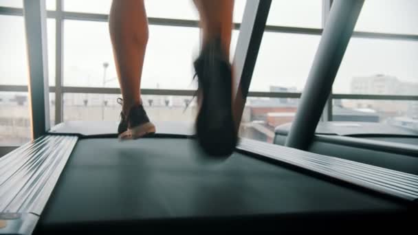 En man som springer på löpbandet framför stora fönster — Stockvideo