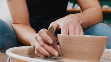 Çömlekçilik - usta kil kasesinin yüzeyini yumuşatmak için özel metal spatulaya yardım ediyor.
