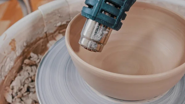 Керамика - человек сушит глиняную чашу со строительным феном — стоковое фото