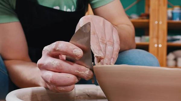 Pottery - the master is helping with a special metal spatula to smooth the surface of the clay bowl — Stock Photo, Image