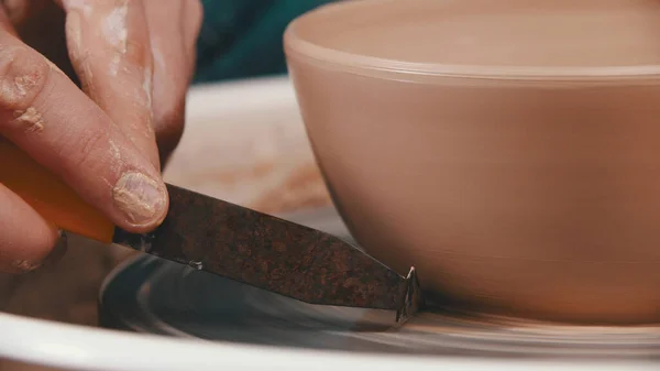Keramik - mästaren hjälper sig själv att ta bort överflödig lera med en speciell modelleringsverktyg — Stockfoto