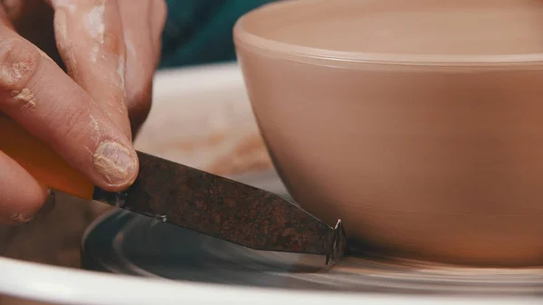 Pottery - the master is helping himself to remove excess clay with a special modeling tool — Stock Photo, Image