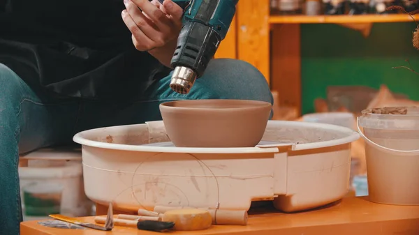 Керамика - человек сушит глиняную чашу со строительным феном — стоковое фото
