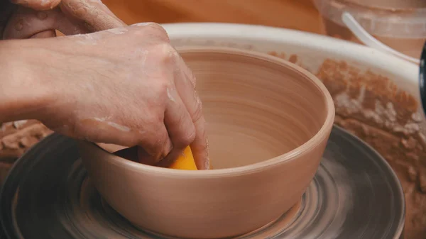 Cerâmica - o homem está limpando o fundo da tigela com uma esponja amarela — Fotografia de Stock