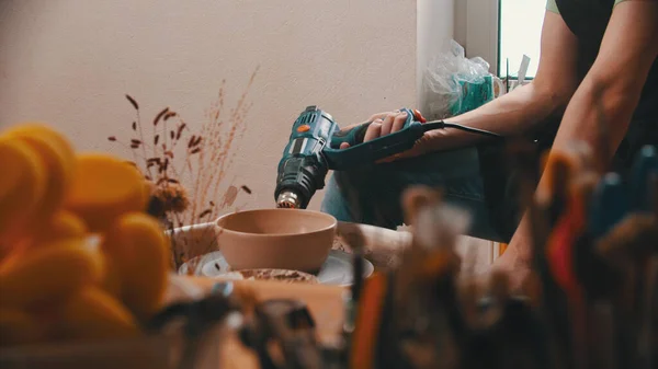 Pottery - the master is sitting in his workshop among his tools and dying the bowl — Stock Photo, Image