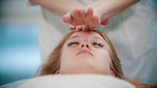Massage - massös knådar sina klienter ansikte med handflator — Stockvideo