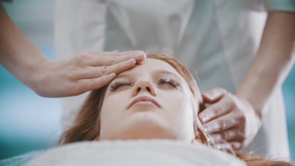 Massage - en massös knådar sina unga klienter pannan — Stockvideo