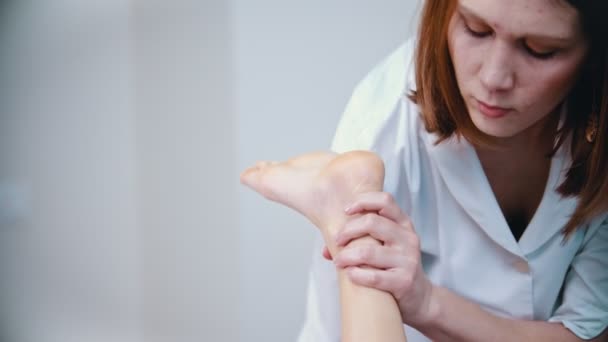 Massage - kvinnlig ung massage terapeut böja ett ben av en klient massera hennes underben — Stockvideo