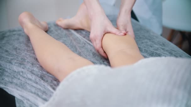 Massage - massage terapeut knådar benen på sin klient med tummar — Stockvideo