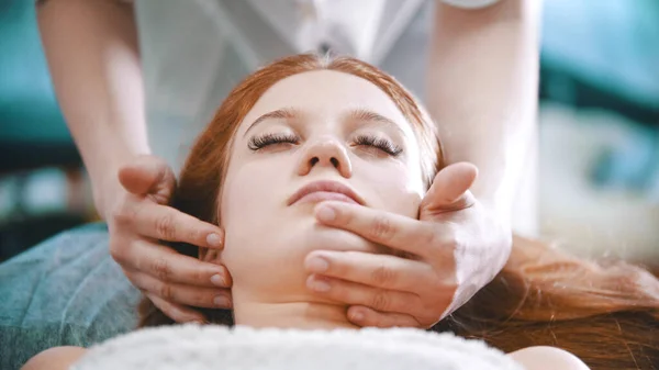 Massage - masseuse kneading the chin area to a young woman using her palms — Stock Photo, Image