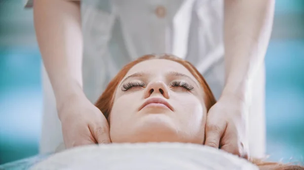 Massage - female masseuse kneading the chin area to a young woman using her palms — Stock Photo, Image