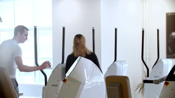 Современный тренажерный зал - мужчина и женщина начинают делать утренние упражнения в тренажерном зале — стоковое видео