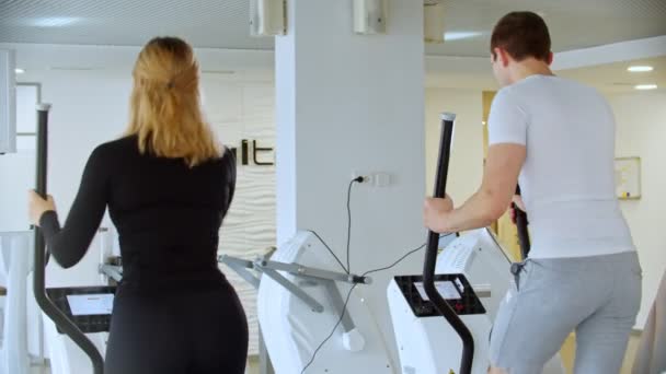 Moderne sportschool - een jonge man en een vrouw werken hard op de ochtend oefeningen in de sportschool — Stockvideo