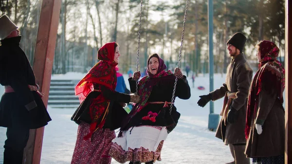 Русский фольклор - русская девушка качается и все смеются в солнечный день — стоковое фото