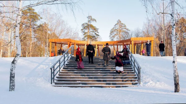 Русский фольклор - молодежь в войлочных сапогах танцует на лестнице в современном зимнем парке — стоковое фото