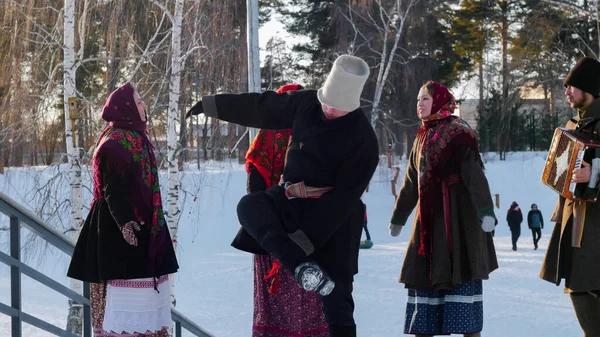 Ρωσική λαογραφία - νέοι άνθρωποι σε τσόχινες μπότες χορεύουν σε εξωτερικούς χώρους το χειμώνα στο πάρκο — Φωτογραφία Αρχείου