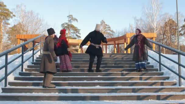 Ruský národ - lidé v tradičním ruském oblečení tančí v zimě na schodech — Stock video