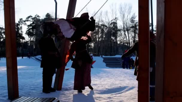 Rosyjski folklor - kobieta w tradycyjnym stroju jeździ na huśtawce w zimowym parku — Wideo stockowe