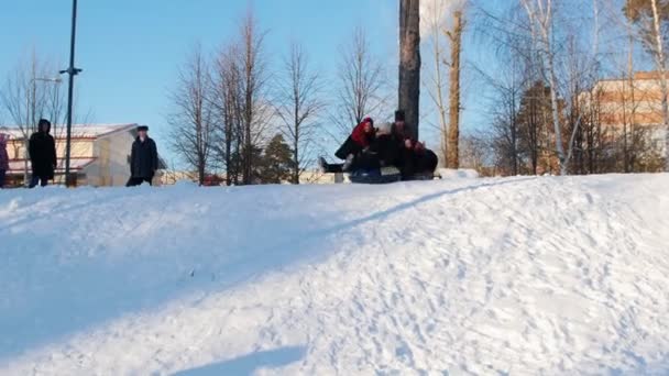 Folclore russo - homens e mulheres em trajes populares russos estão montando um slide de neve — Vídeo de Stock