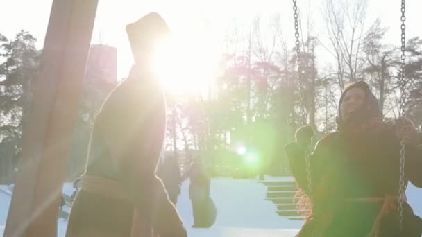Pueblo ruso - mujer en una bufanda brillante está montando en un columpio y riendo — Vídeos de Stock