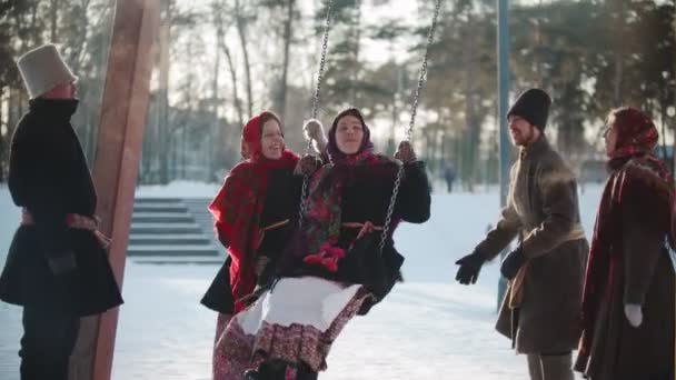 Folclore russo - Menina russa balançando e todo mundo está rindo em um dia ensolarado — Vídeo de Stock